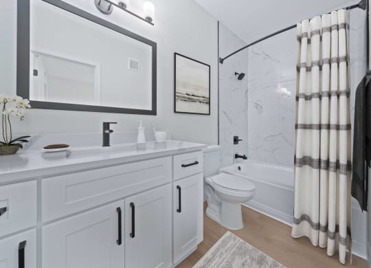 a bathroom with white cabinetry and a shower and a toilet